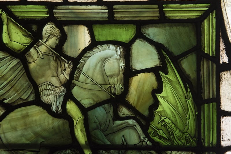 A close-up of a stained-glass window at Chartered Accountant's Hall, showing St. George on a horse thrusting a spear into the mouth of a dragon.