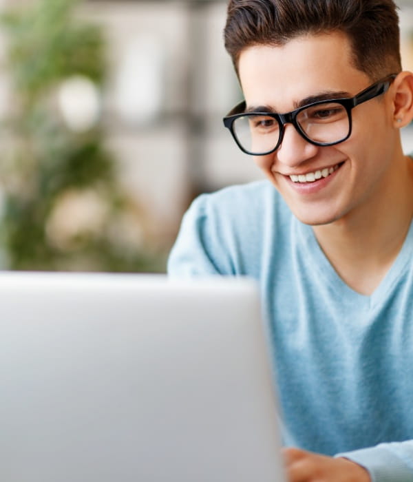 Young man wearing glasses looking at laptop screen