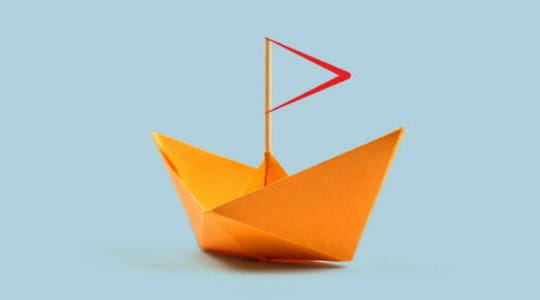 Orange origami boat with the ICAEW dividers representing a sail