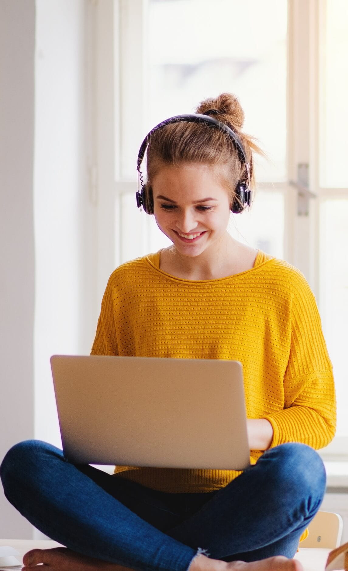 Young woman in yellow top wearing headphones