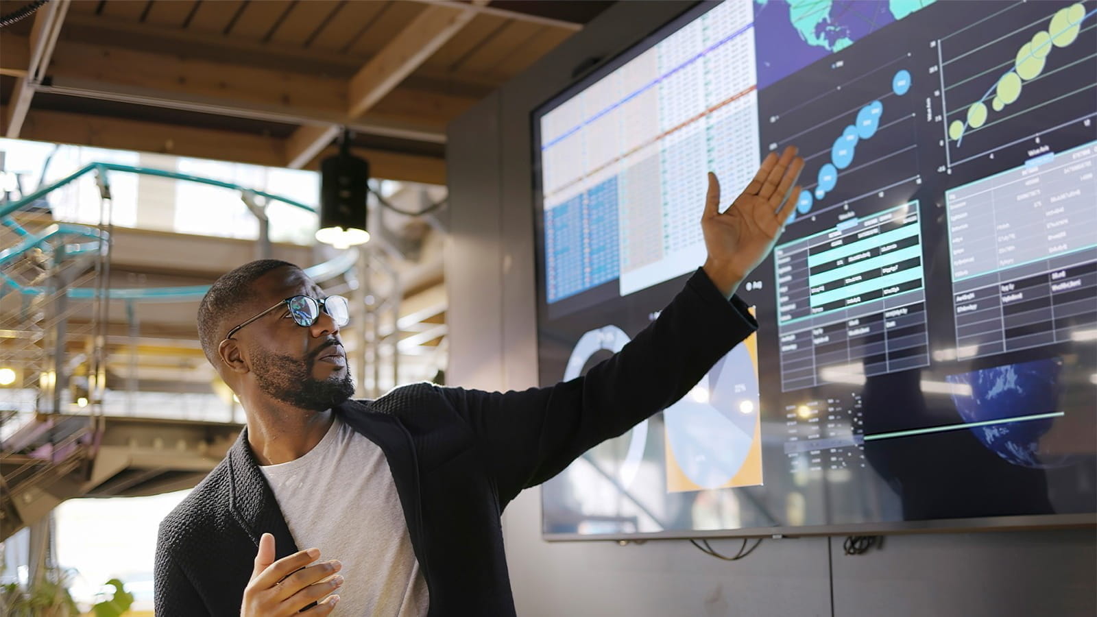 man employee pointing to digital screens monitors displaying graphs charts office corporate