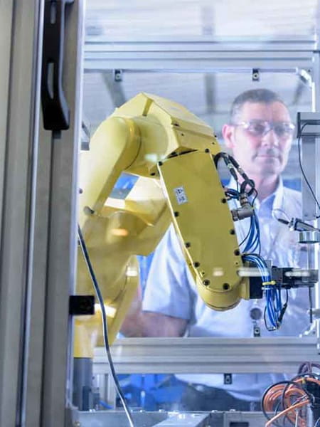 man employee engineer working in front of yellow robot machinery
