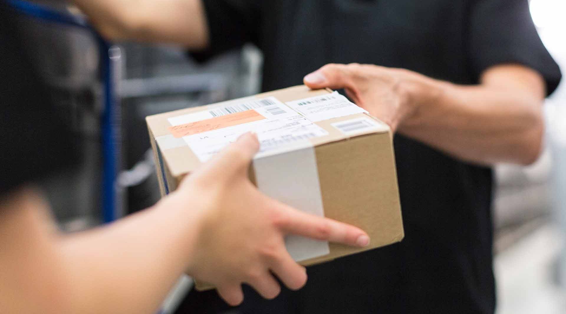 parcel box delivery passing between two people hands trade paperwork black shirts